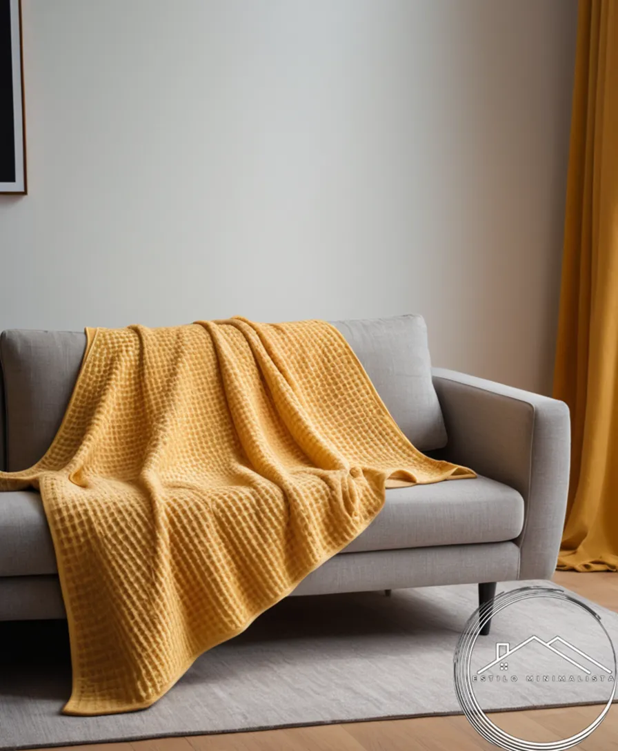 A minimalist waffle-patterned throw blanket draped over a modern sofa.