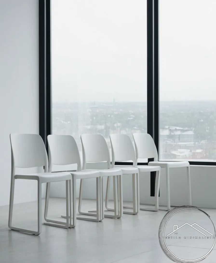 3-4 minimalist white chairs stacked or leaning against each other.